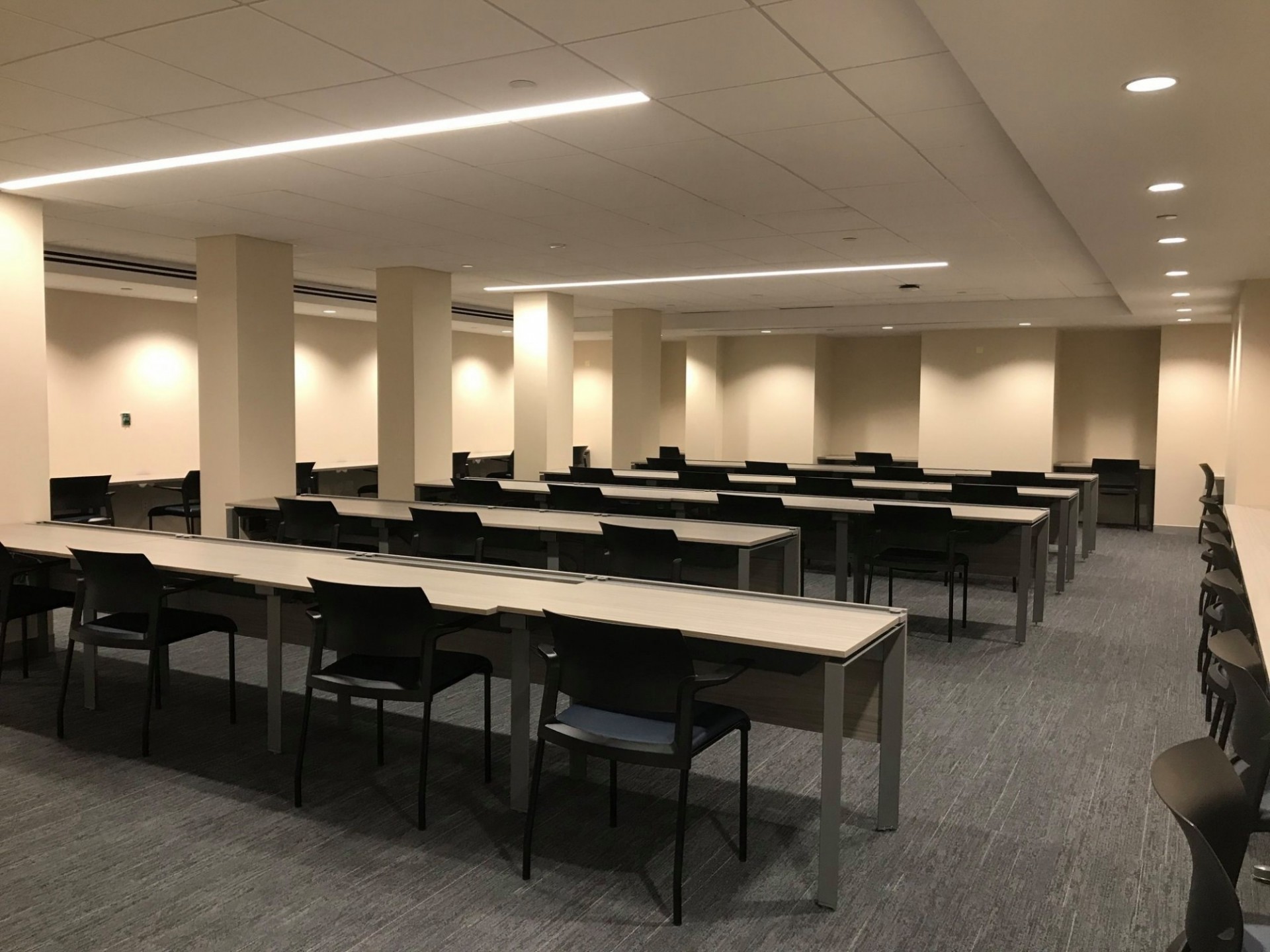 Rows of desks and chairs in a well-lit classroom